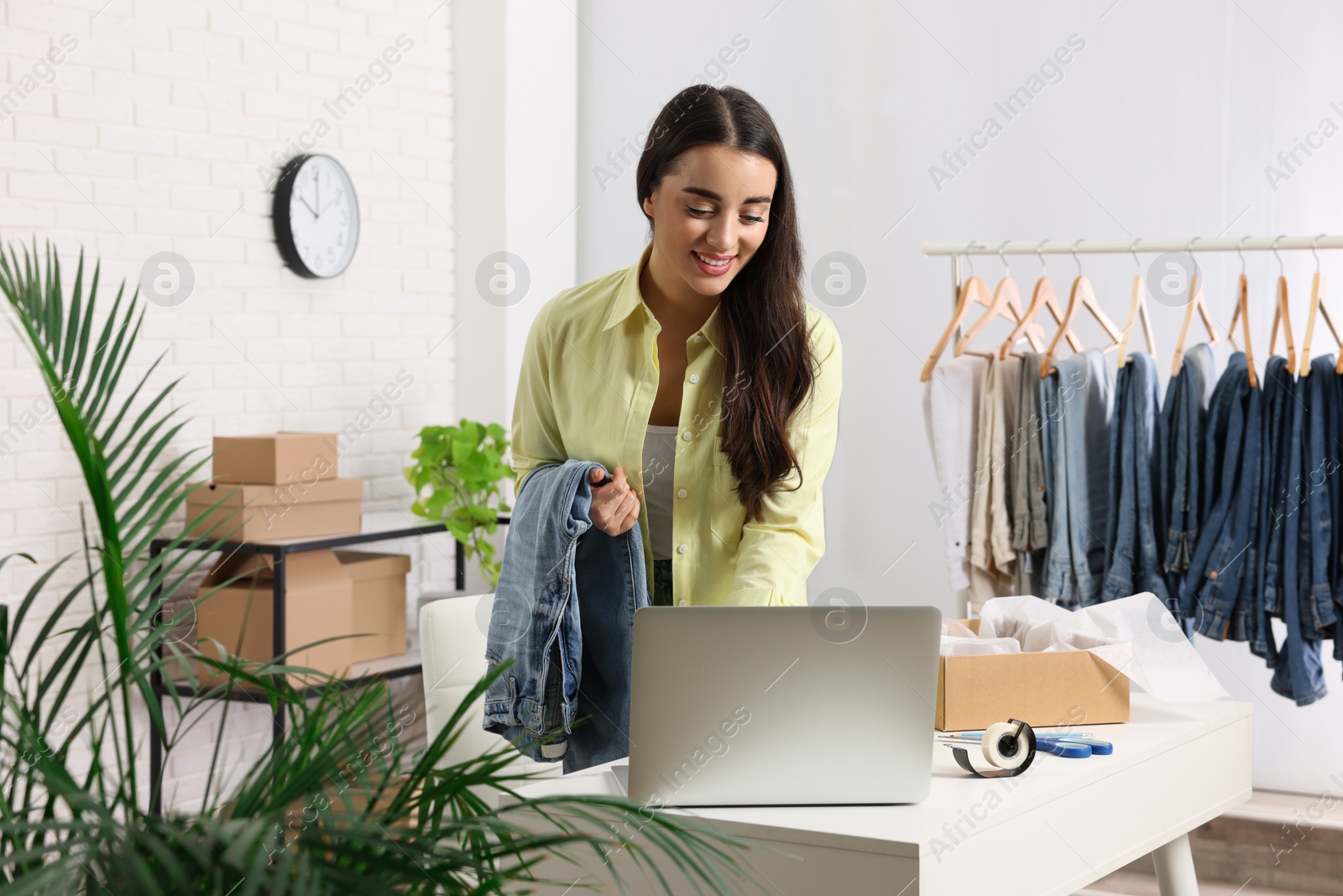 Photo of Clothes seller using laptop at workplace. Online store