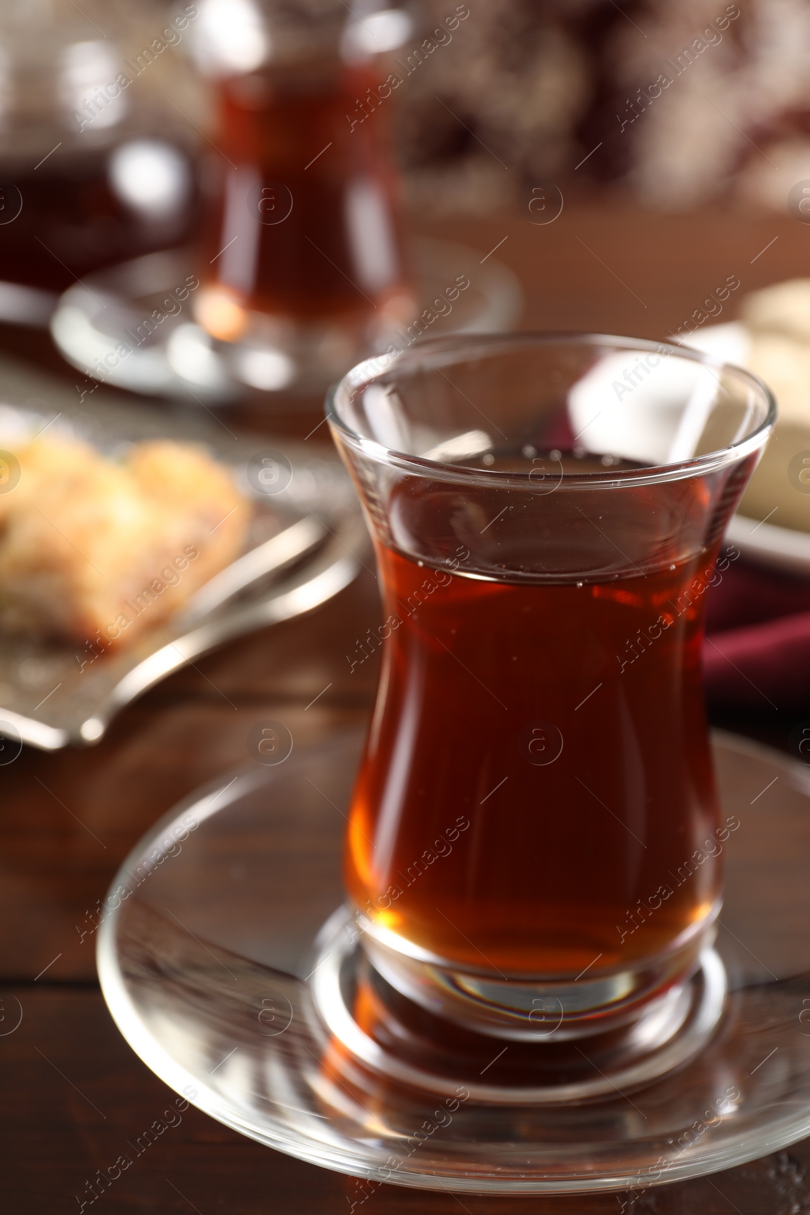 Photo of Traditional Turkish tea in glass on wooden table, closeup