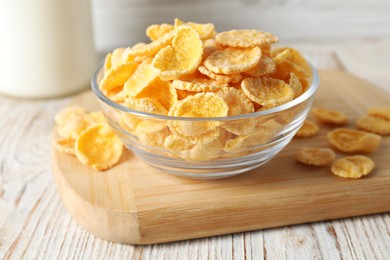 Photo of Glass bowl of tasty crispy corn flakes on white wooden table
