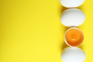 Photo of Fresh raw chicken eggs on yellow background, flat lay. Space for text