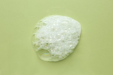 Photo of Drop of bath foam on light green background, top view