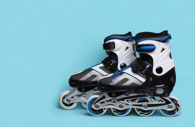 Photo of Pair of inline roller skates on color background. Space for text