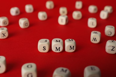 Wooden cubes with abbreviation SMM (Social media marketing) on red background