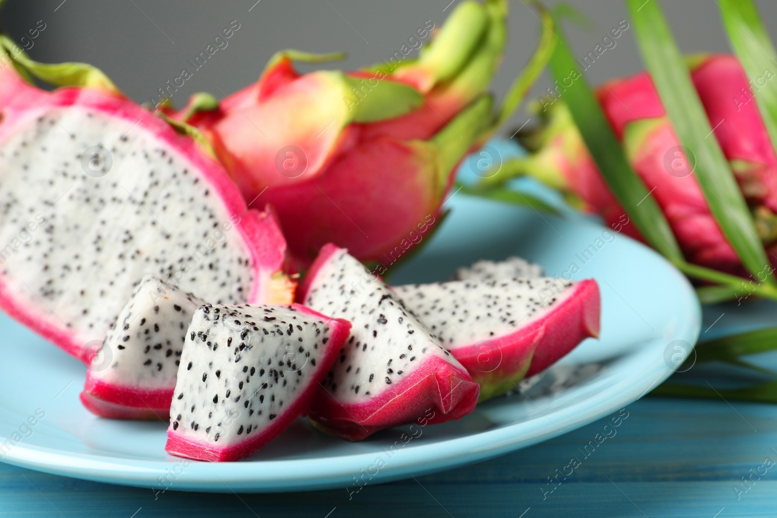 Photo of Plate with delicious cut and whole white pitahaya fruits on table, closeup