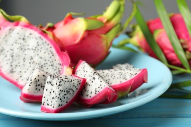 Photo of Plate with delicious cut and whole white pitahaya fruits on table, closeup