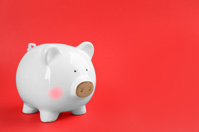White piggy bank on red background. Space for text