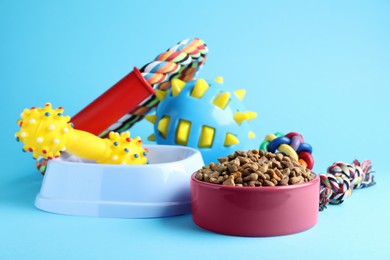Photo of Feeding bowls and toys for pet on light blue  background