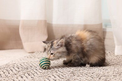 Photo of Cute fluffy kitten with ball at home