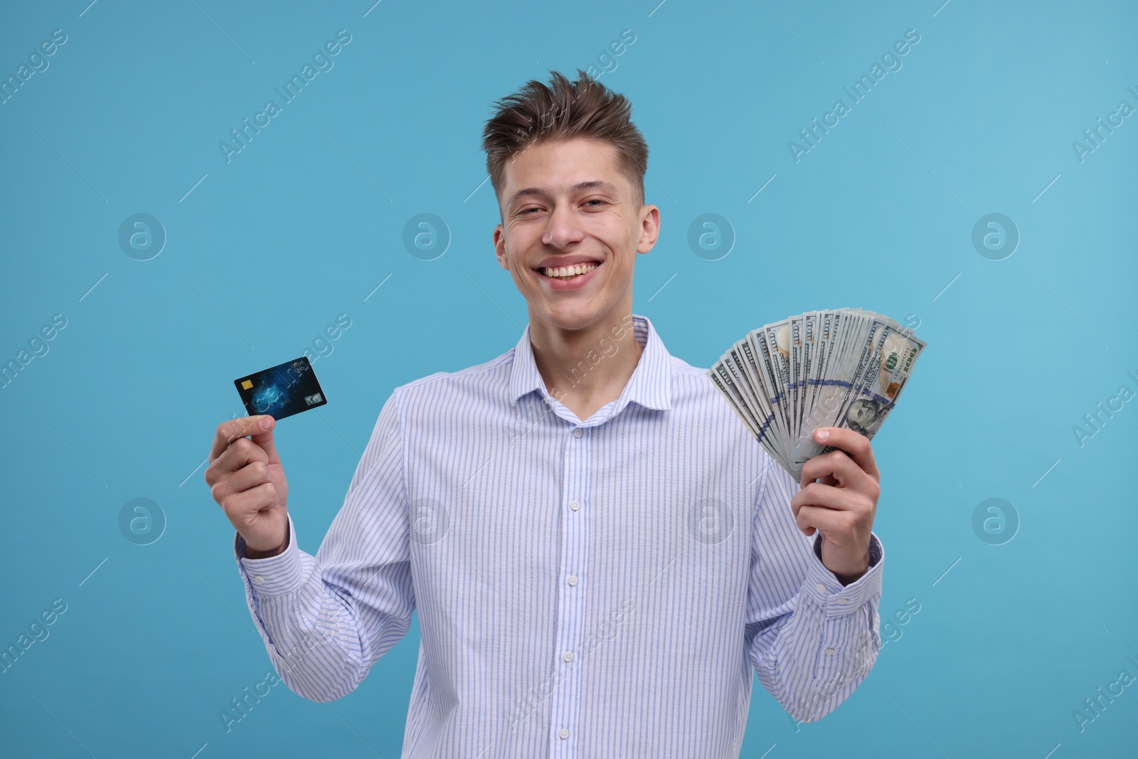 Photo of Happy man with credit card and dollar banknotes on light blue background