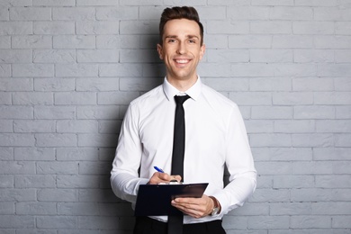 Photo of Male real estate agent with clipboard on brick wall background