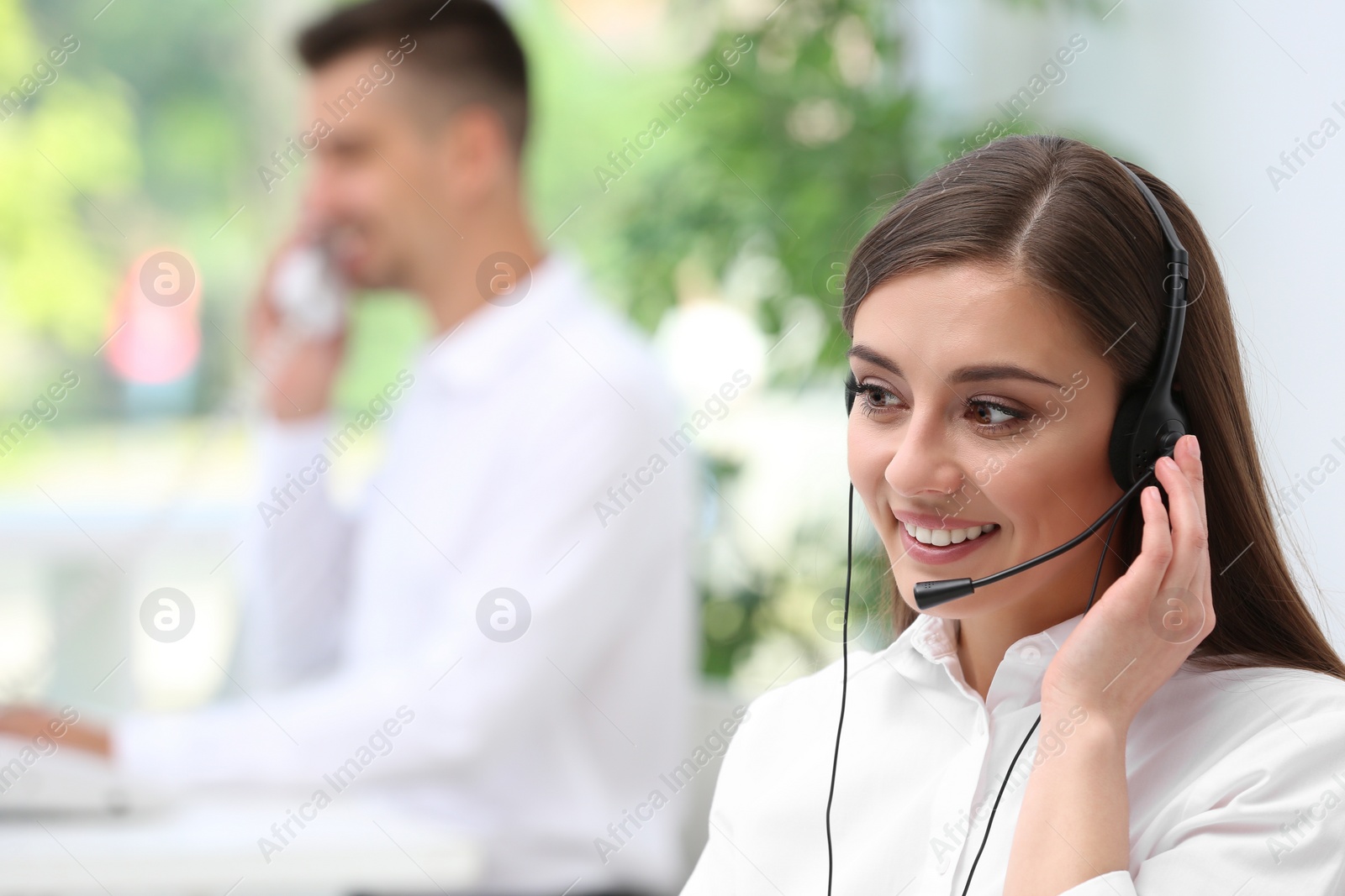 Photo of Young female receptionist with headset in office