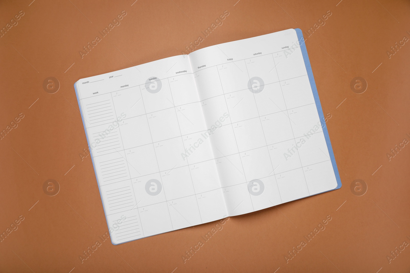 Photo of Open monthly planner on brown background, top view