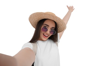 Smiling young woman in sunglasses and straw hat taking selfie on white background