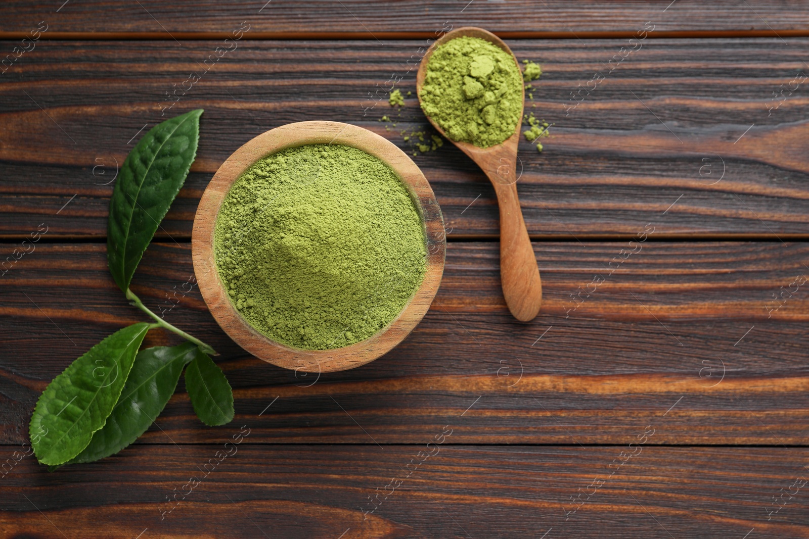 Photo of Bowl and spoon with green matcha powder on wooden table, flat lay. Space for text