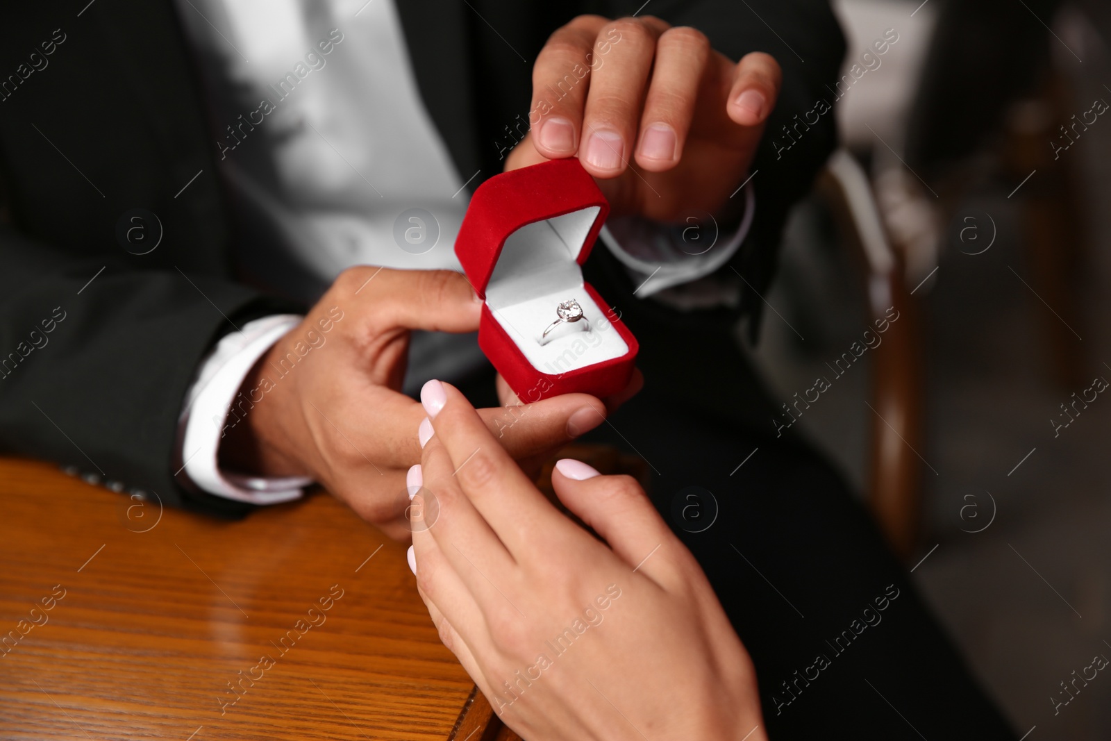 Photo of Man with engagement ring making proposal to his girlfriend at table, closeup