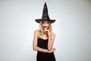 Photo of Beautiful woman in witch costume on white background. Halloween party