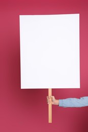 Photo of Woman holding blank sign on pink background, closeup. Space for design