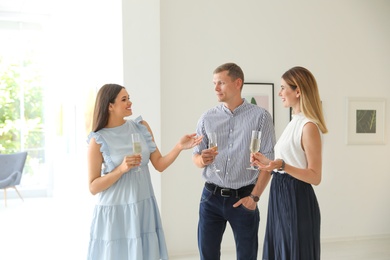 Group of people with glasses of champagne at exhibition in art gallery