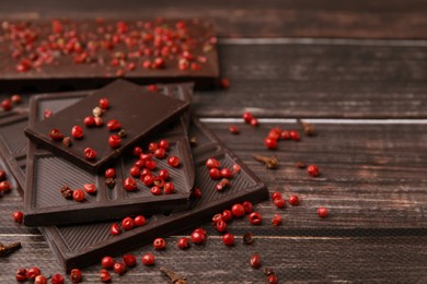 Photo of Delicious chocolate and red peppercorns on wooden table, closeup. Space for text