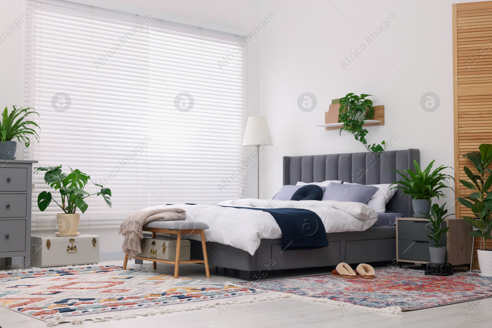 Photo of Stylish bedroom with double bed and beautiful green houseplants. Modern interior