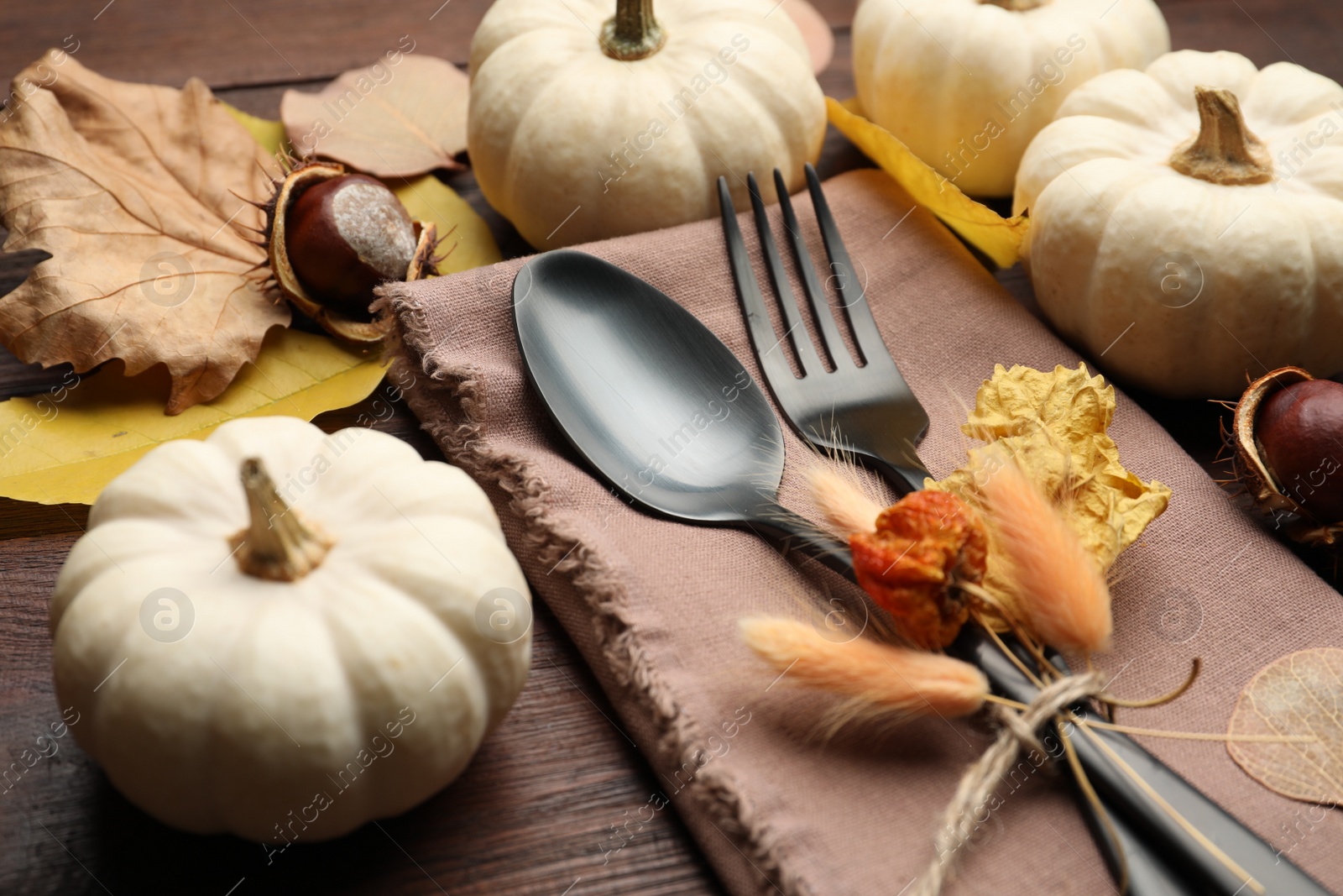 Photo of Autumn table setting, closeup, Cutlery with pumpkins and fallen leaves on wooden table