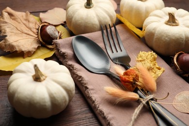 Autumn table setting, closeup, Cutlery with pumpkins and fallen leaves on wooden table