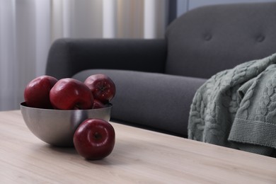 Photo of Red apples in bowl on wooden coffee table indoors