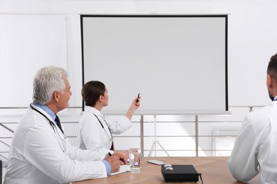 Photo of Team of doctors using video projector during conference indoors