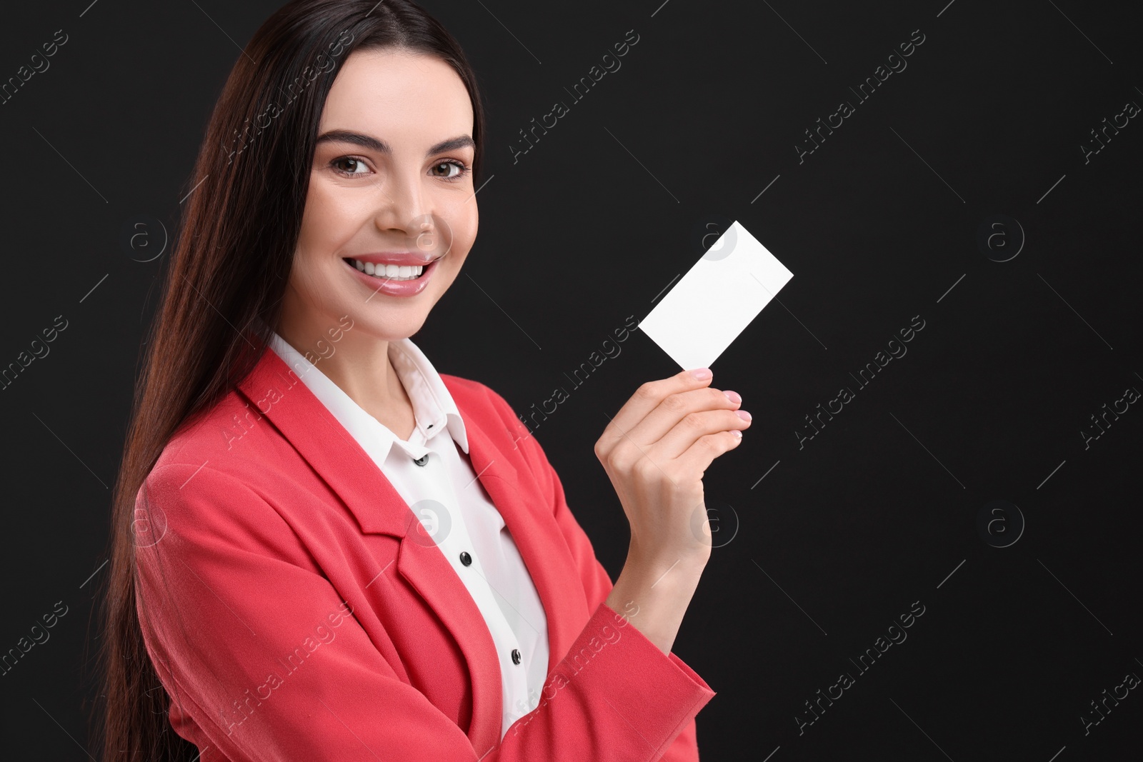 Photo of Happy woman holding blank business card on black background. Space for text