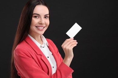 Photo of Happy woman holding blank business card on black background. Space for text