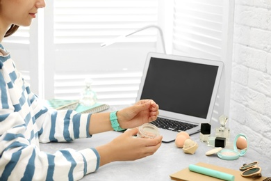 Young beauty blogger with ball blush at light grey marble table, closeup