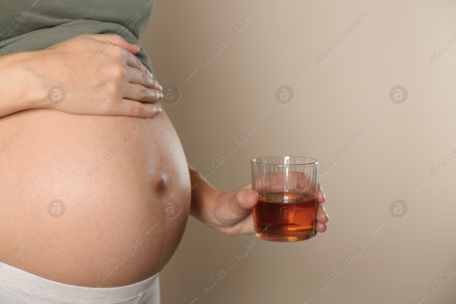 Photo of Pregnant woman with glass of whiskey on color background. Alcohol addiction