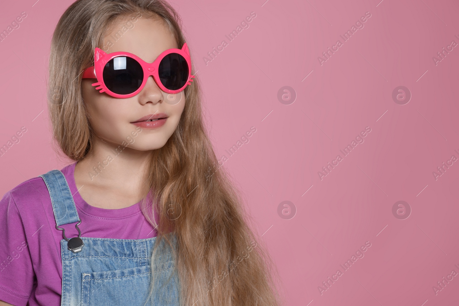Photo of Girl in stylish sunglasses on pink background, space for text