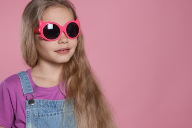 Photo of Girl in stylish sunglasses on pink background, space for text