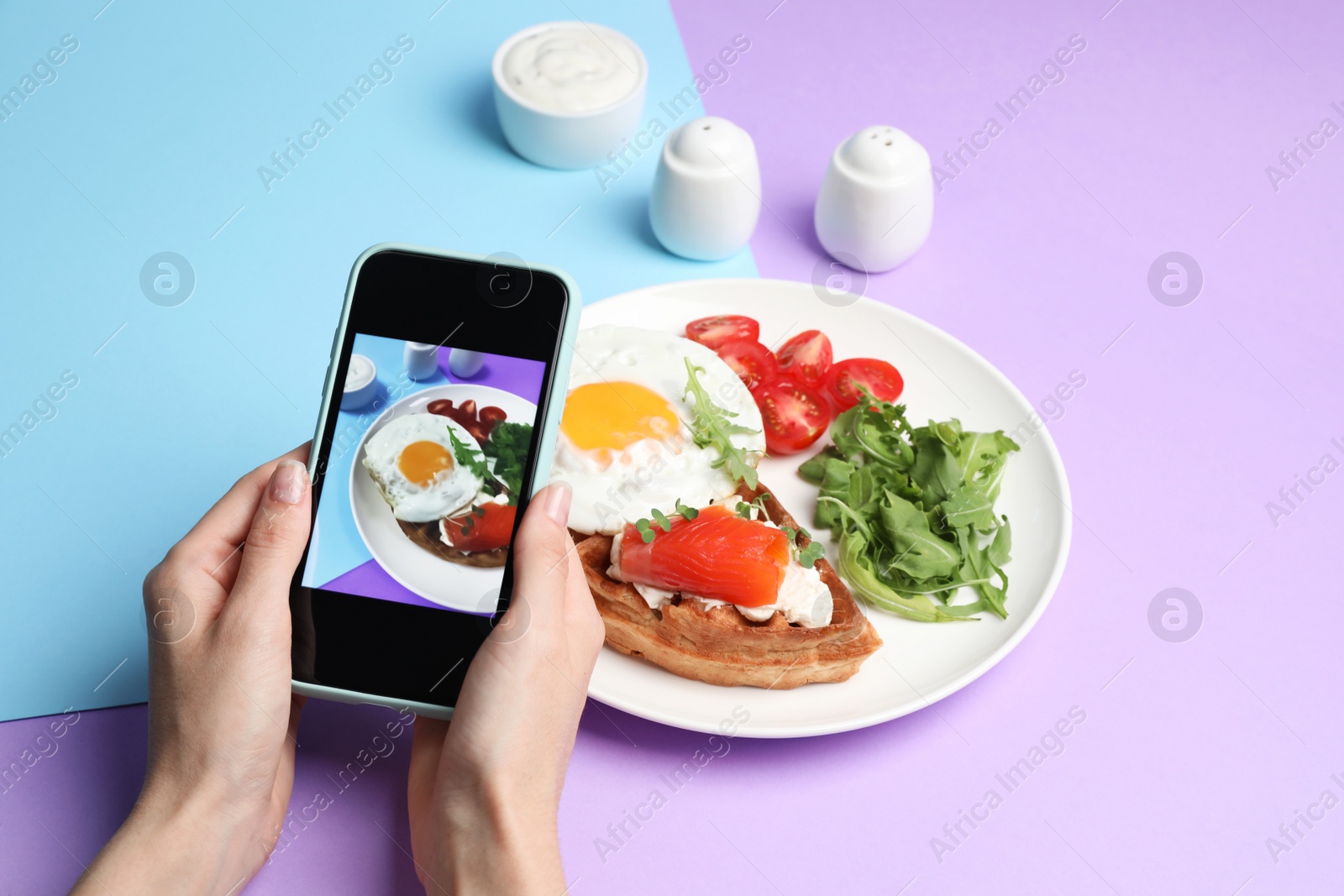 Photo of Woman taking photo of delicious breakfast on color background, closeup