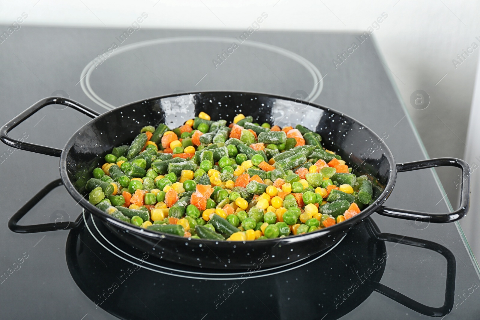 Photo of Cooking tasty frozen vegetable mix on induction stove