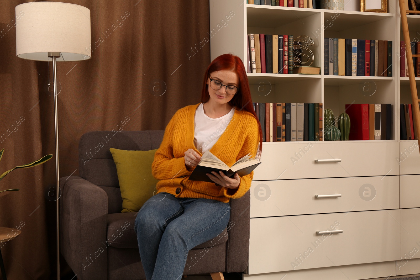 Photo of Beautiful young woman reading book in armchair indoors. Home library