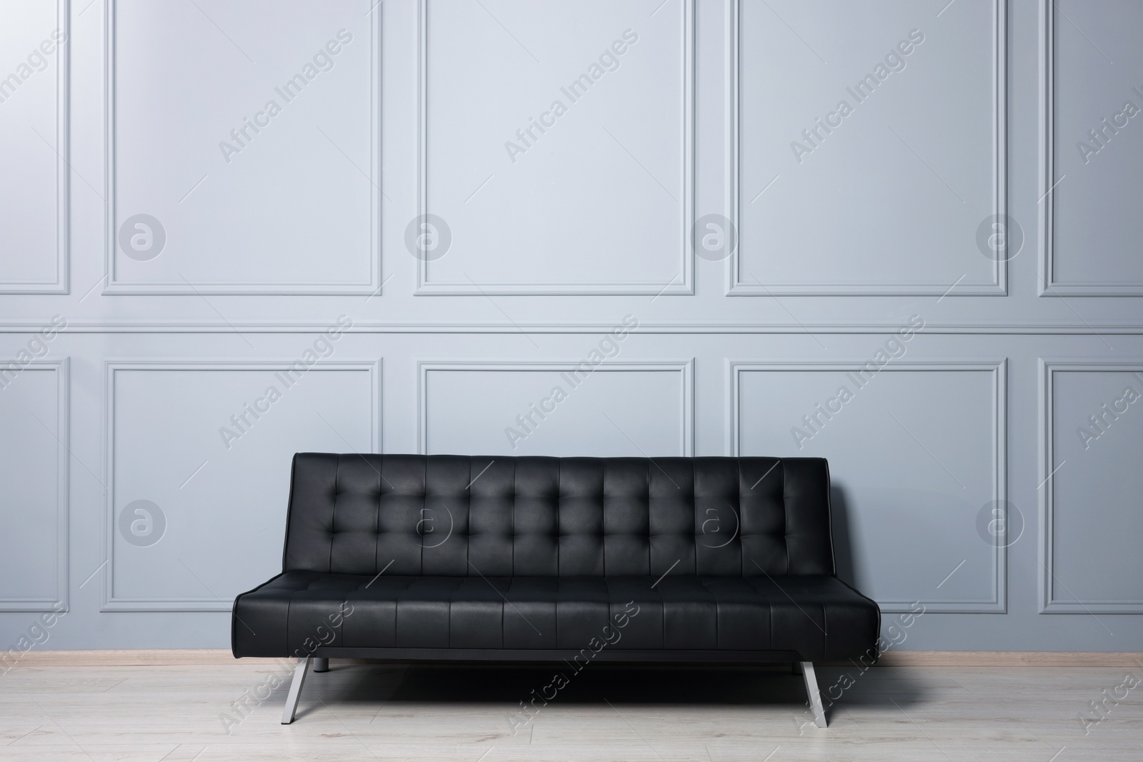 Photo of Stylish leather sofa near white wall in room. Interior design