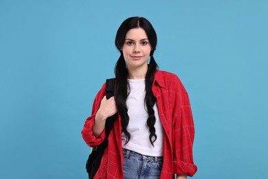 Student with backpack on light blue background