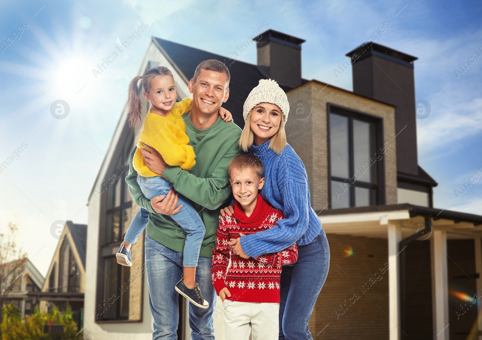 Image of Happy family standing in front of their house on sunny day 