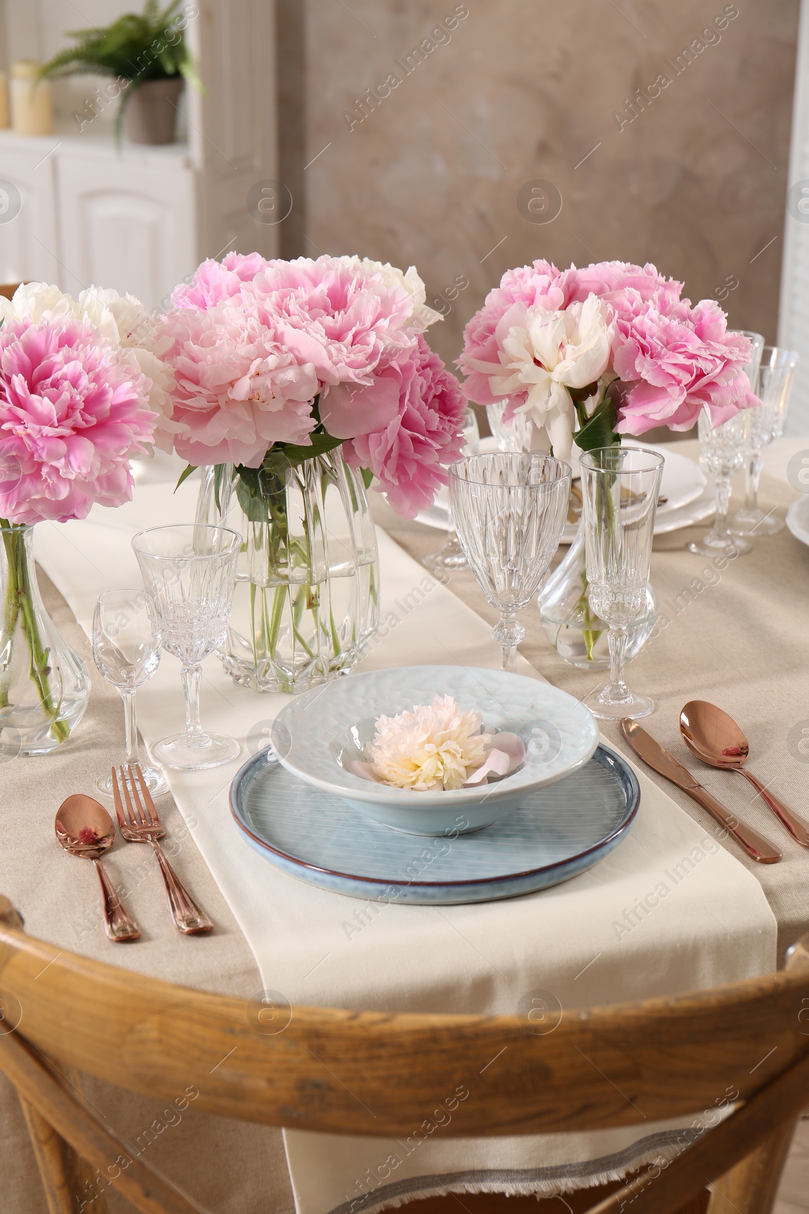 Photo of Stylish table setting with beautiful peonies and golden cutlery indoors