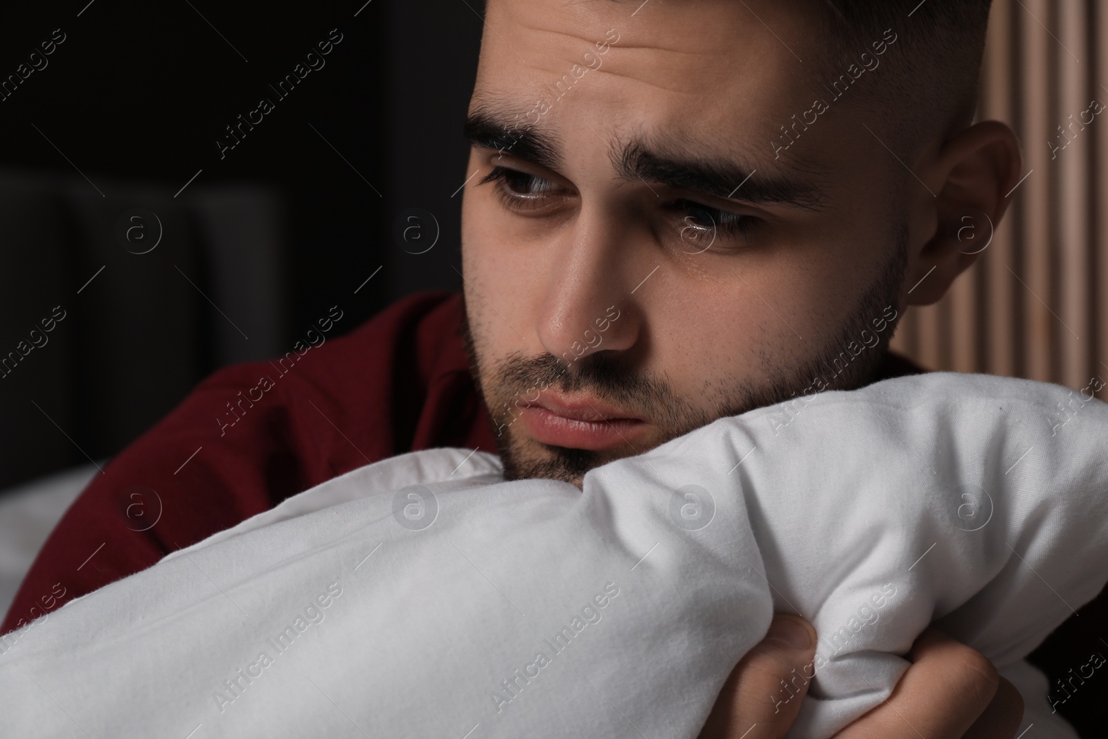 Photo of Sad young man with pillow at home