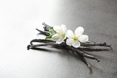 Photo of Vanilla sticks and flowers on grey background