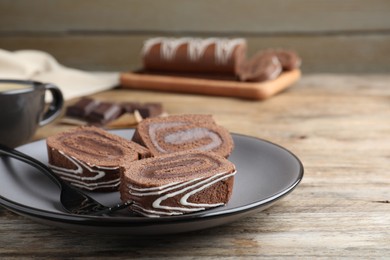 Tasty chocolate cake roll with cream on wooden table, closeup
