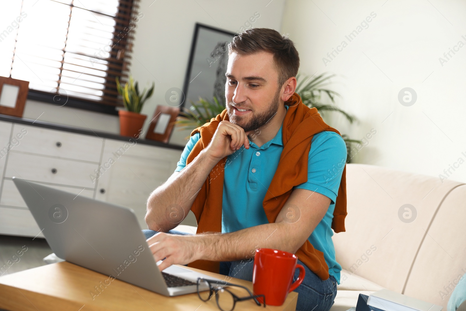 Photo of Young man using laptop at table indoors