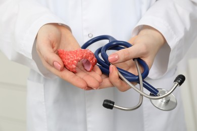 Photo of Endocrinologist holding stethoscope and model of thyroid gland, closeup