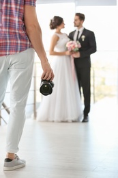 Photo of Professional photographer with camera and wedding couple in studio