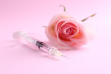 Photo of Cosmetology. Medical syringe and rose flower on pink background, closeup