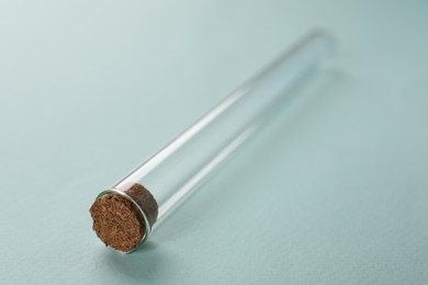 Photo of Test tube on turquoise background, closeup. Laboratory glassware