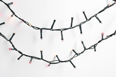 Photo of Beautiful Christmas lights on white background, top view